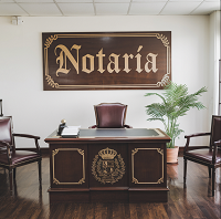 Interior de una notaría, despacho con una mesa y sillas marrón oscuro.