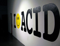 Foto de un cartel blanco con la palabra  I -like ACID en negro. Eñ like, es un emotion.