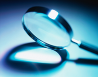 Una lupa colocada a 45 grados de la horizontal, sobre una mesa. Todo en tonos azules.