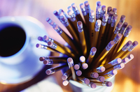 Lapicero con lápices de colores sobre una mesa junto a una taza de café.