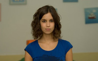 Mujer joven, de pie, con camisa azul y mirando de frente.