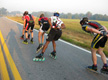 Se ven a 5 patinadores en línea patinando por una carretera.