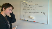 Fotografía de un estudiante intentando solucionar en un encerado una expresión regular.