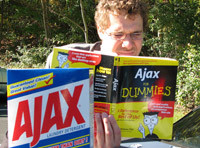 Fotografía de una persona leyendo un libro de Ajax, con un producto de limpieza Ajax al lado.