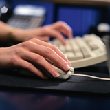 Manos de una persona sobre un teclado y un ratón.