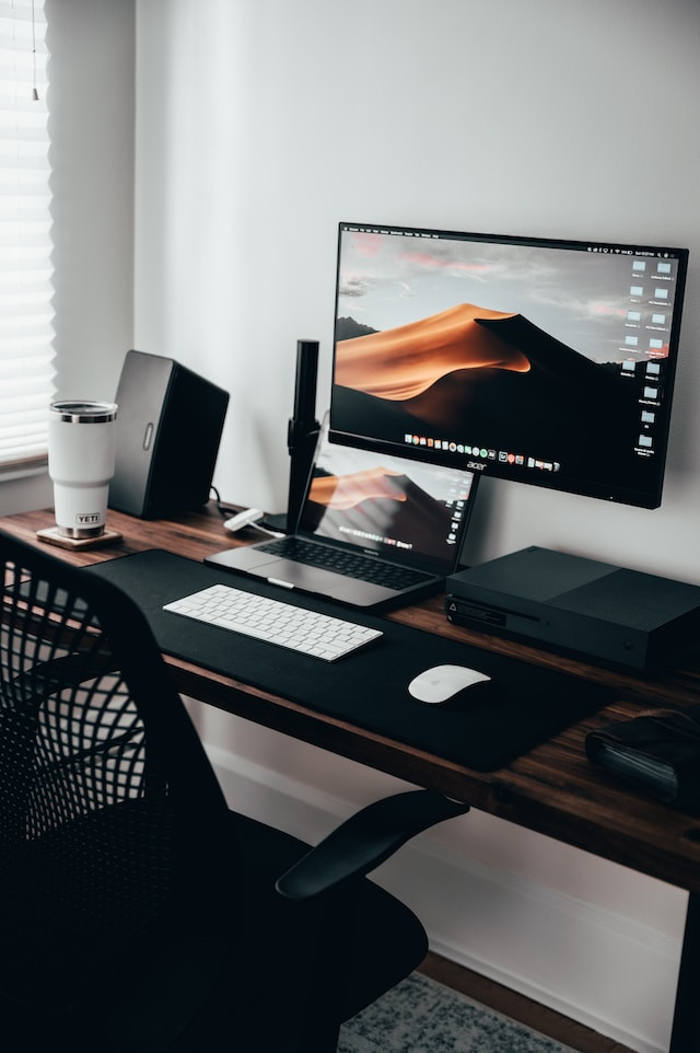 Oficina de teletrabajo con portátil y ordenador.