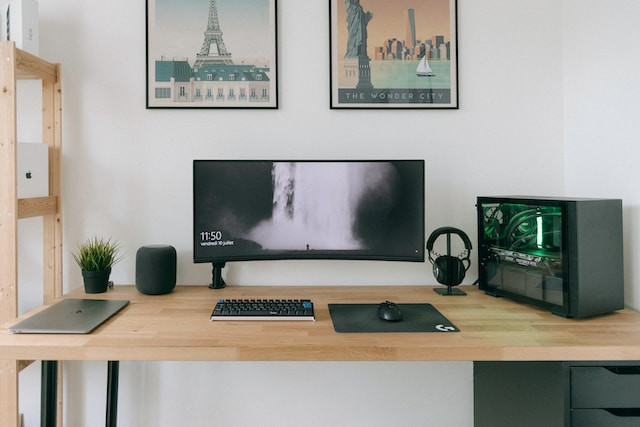 Zona de trabajo con monitor grande, torre y teclado y ratón inalámbricos.