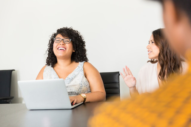 Foto de una reunión con dos mujeres y un hombre sentados alrededor de una mesa.