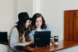 Dos mujeres trabajando y mirando un portátil juntas.