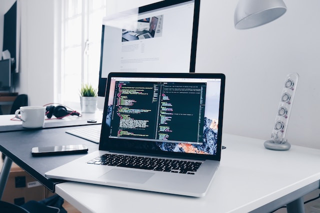 Un portátil con líneas de código en su pantalla sobre un escritorio.
