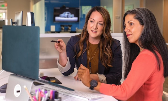 Dos mujeres trabajando delante de un portátil.