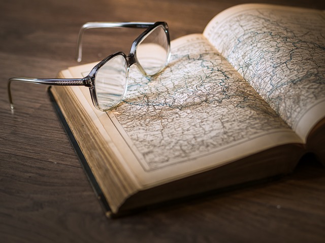 Imagen que muestra un atlas abierto sobre el que se posan unas gafas de lectura.