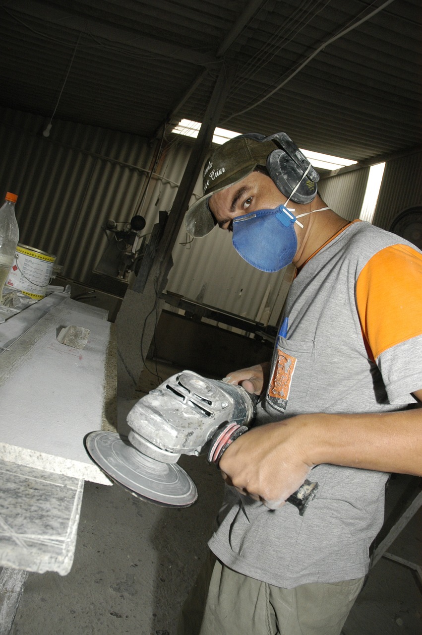Hombre trabajando con mármol y utilizando equipos de protección individual para evitar daños a su salud. 