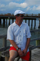 Félix sentado en un banco de madera en el puerto.