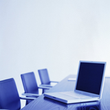 Sobre una mesa de reuniones, un portátil abierto.