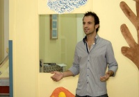 Juan de pie hablando, gesticulando con los brazos.